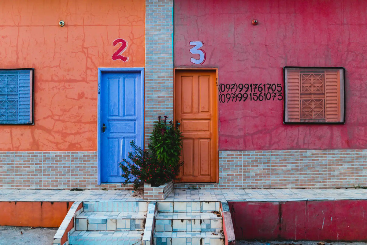 Blaue Tür mit roter Nummer zwei an roter Wand, Ziegelstruktur.